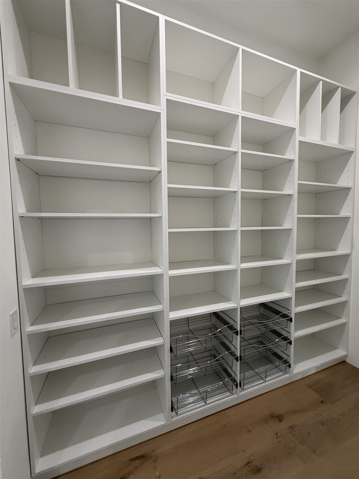 Floor-to-ceiling white shelving with pull-out baskets