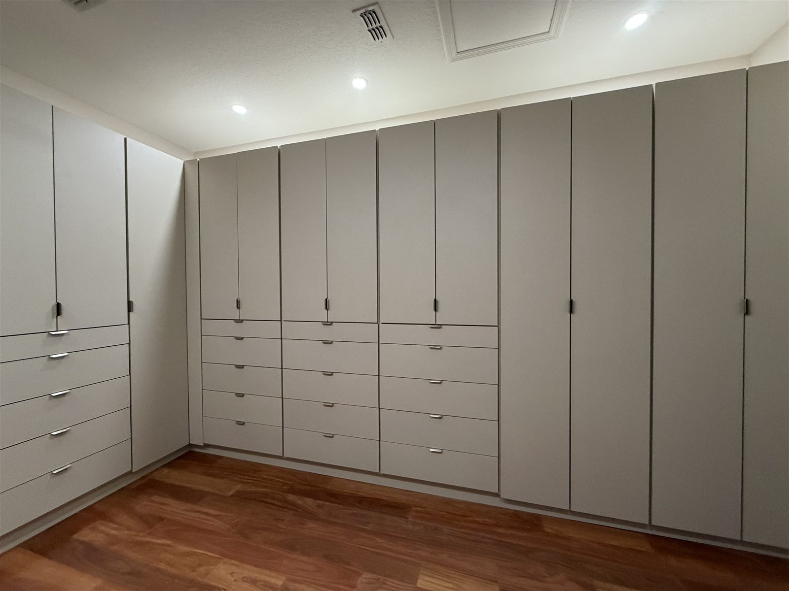 Full-wall warm grey dressing room with drawer banks